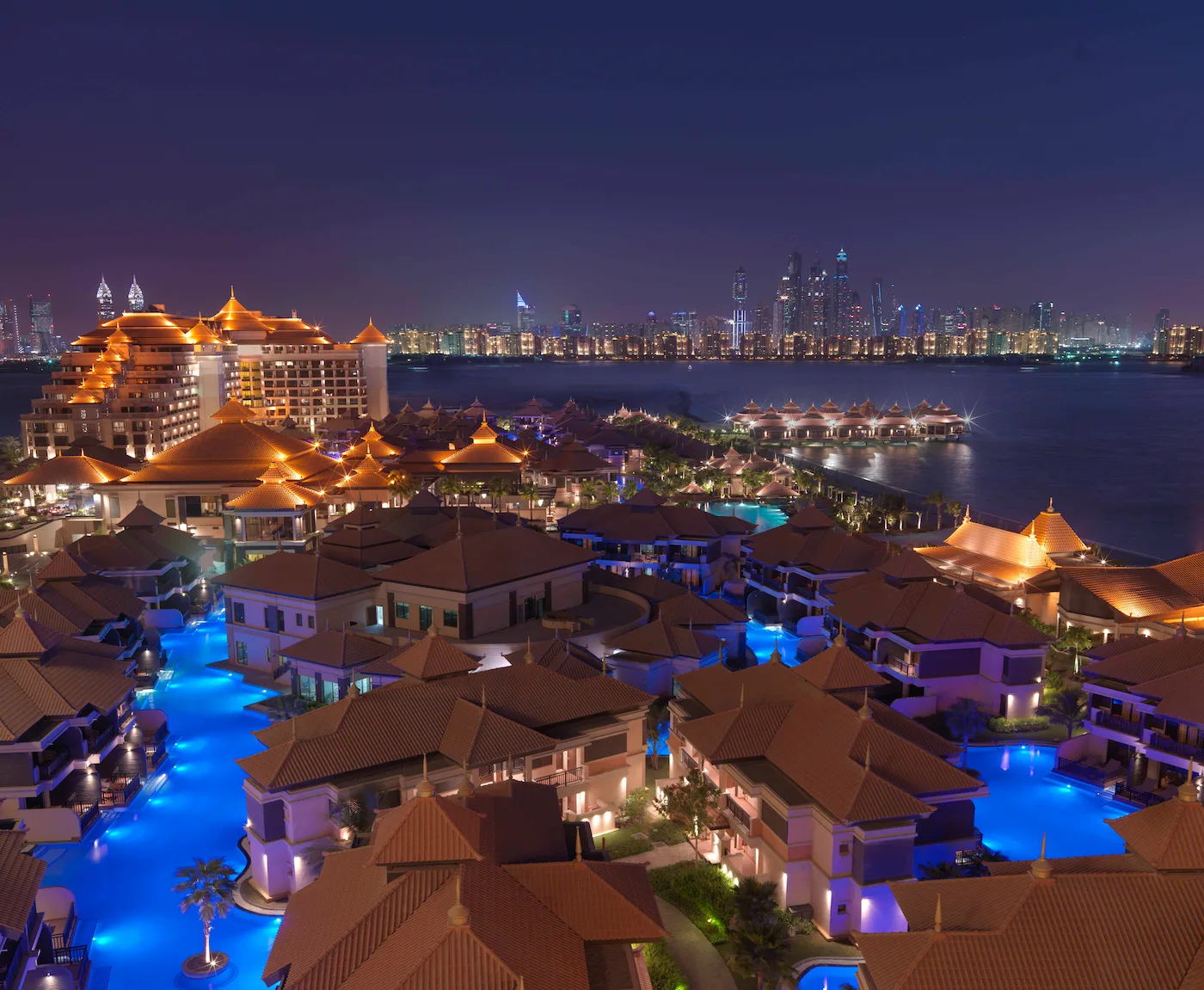 night view of anantara the palm dubai resort exterior with illuminated architecture and pool area