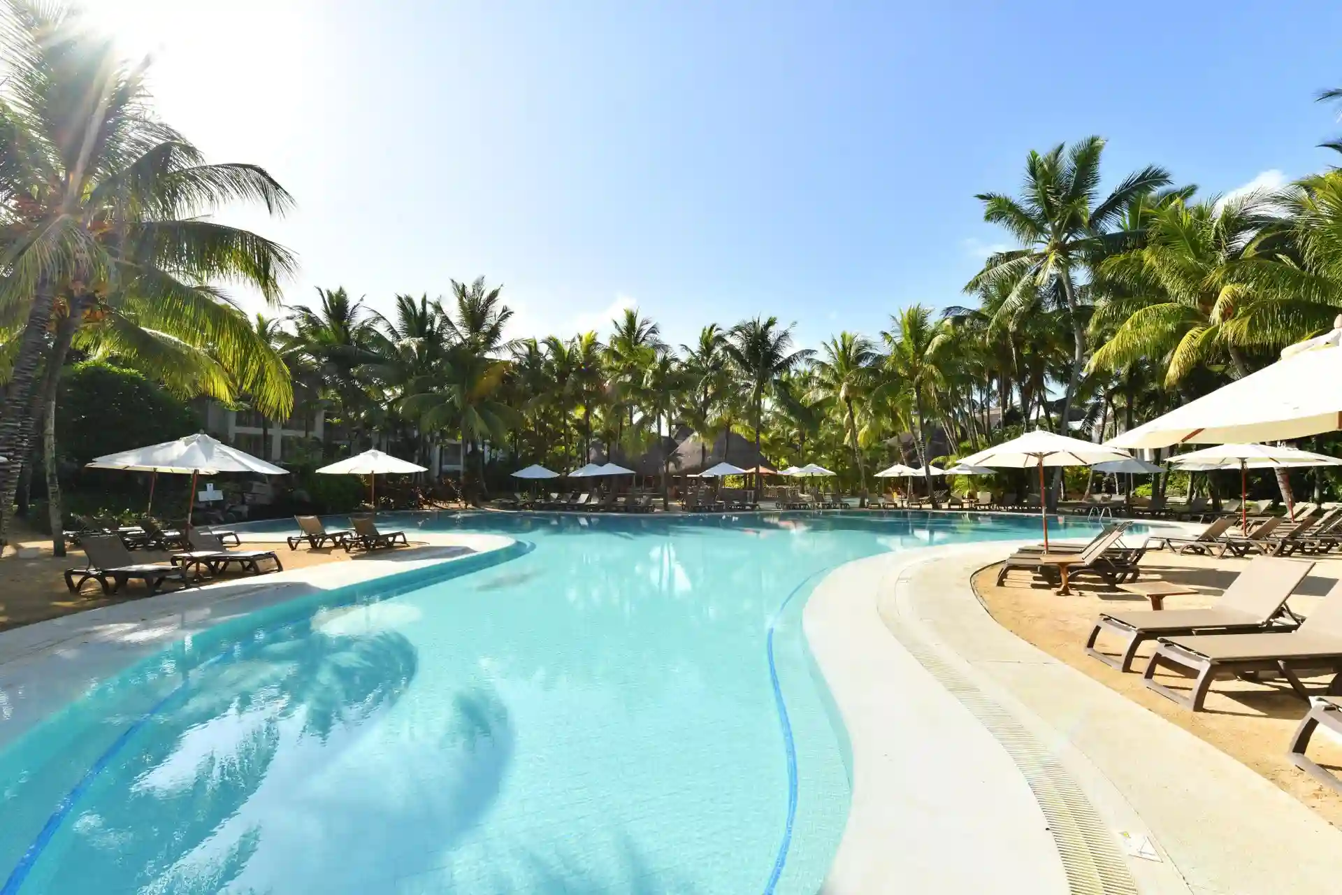 large swimming pool at cannonier mauritius surrounded by palm trees and sun loungers