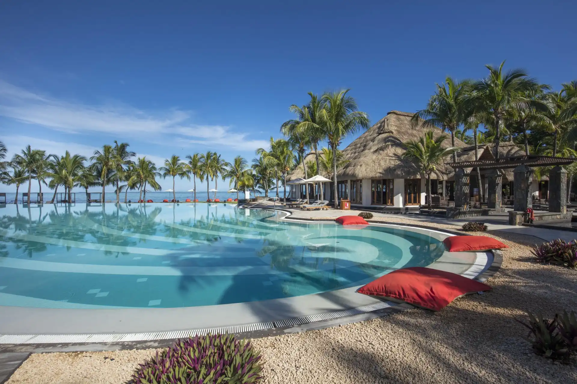 dinarobin mauritius poolside restaurant with dining tables, umbrellas, and tropical surroundings