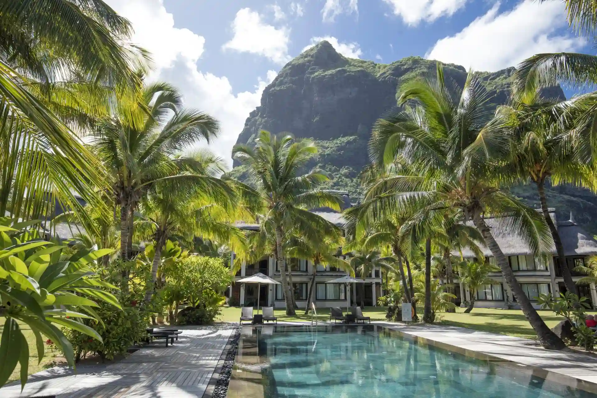 dinarobin mauritius resort pool with sun loungers, umbrellas, and tropical gardens