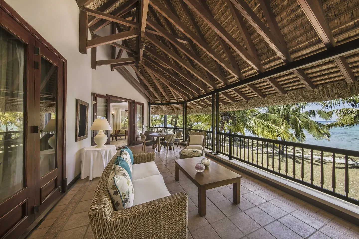 dinarobin senior suite balcony with ocean view, lounge seating, and tropical surroundings