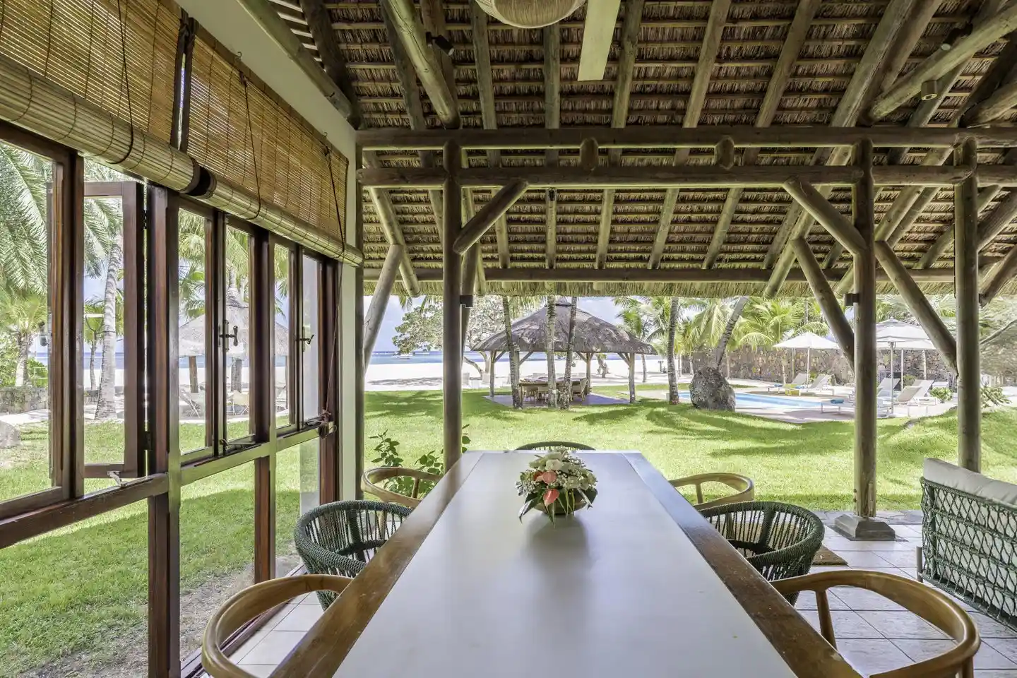 dinarobin villa dining area with table and chairs overlooking tropical garden and pool