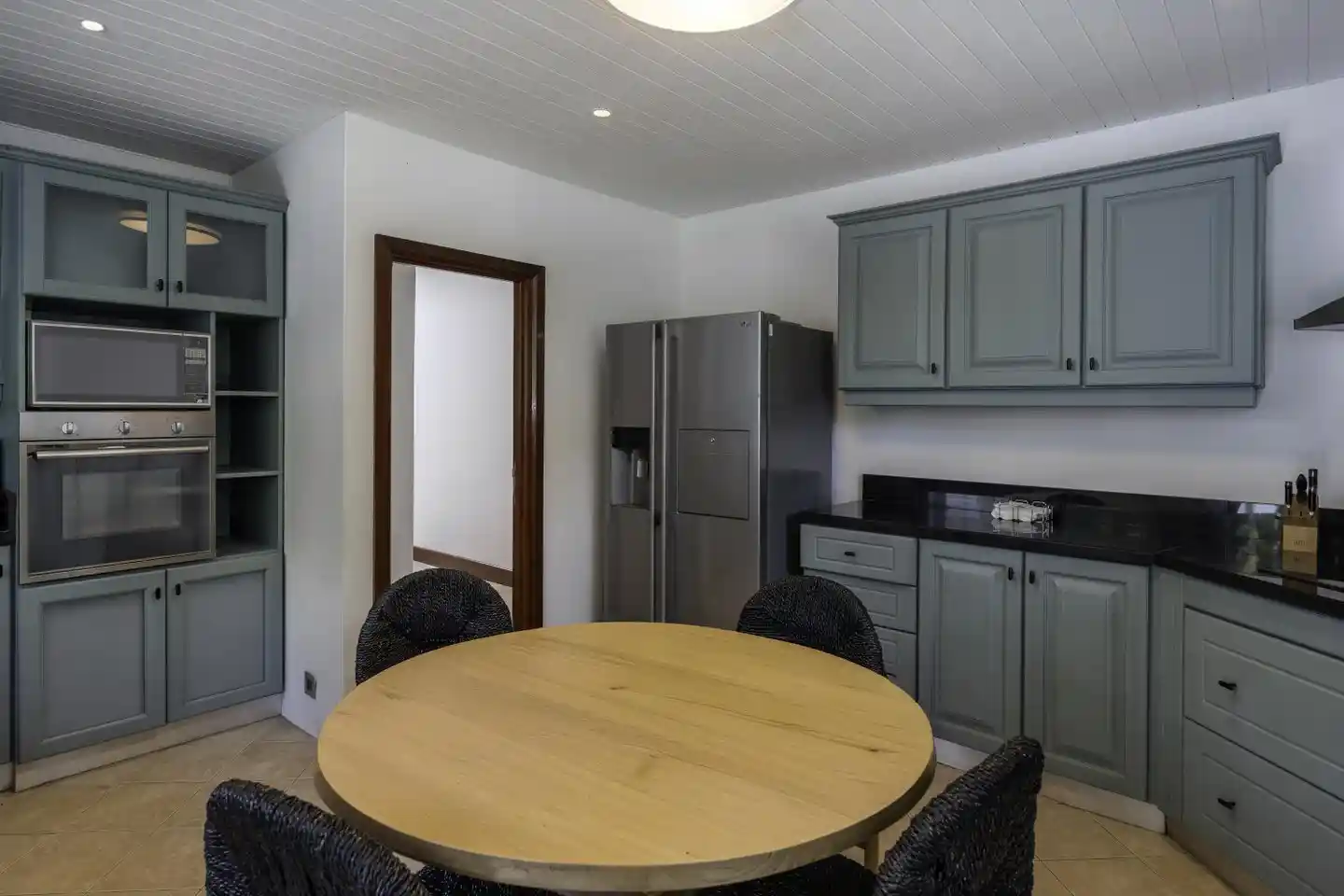 dinarobin villa modern kitchen with appliances, countertop, and tropical view through window