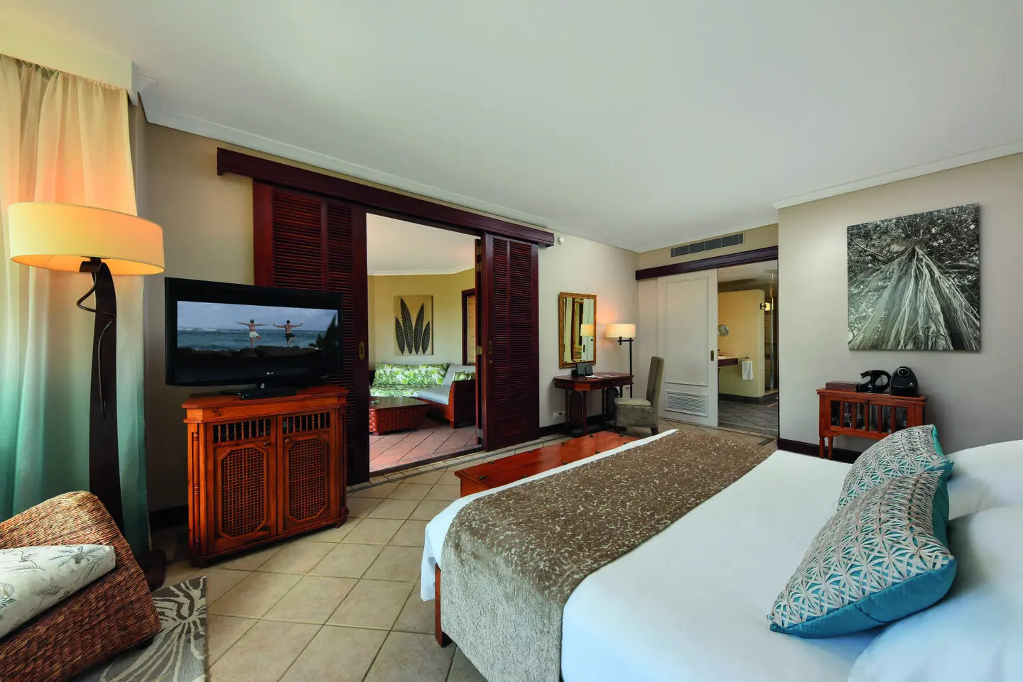 dinarobin zen suite beachfront bedroom with king bed, flat-screen tv, and tropical decor