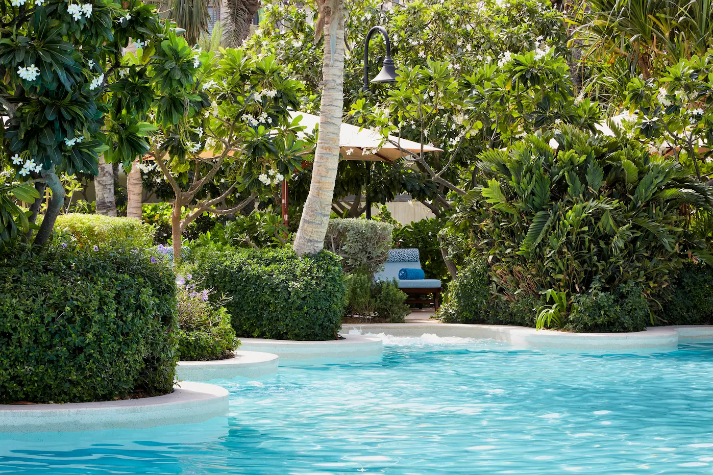 executive pool club landscaping at Jumeirah Beach Hotel featuring tropical planting, shaded pathways and stylish outdoor relaxation areas