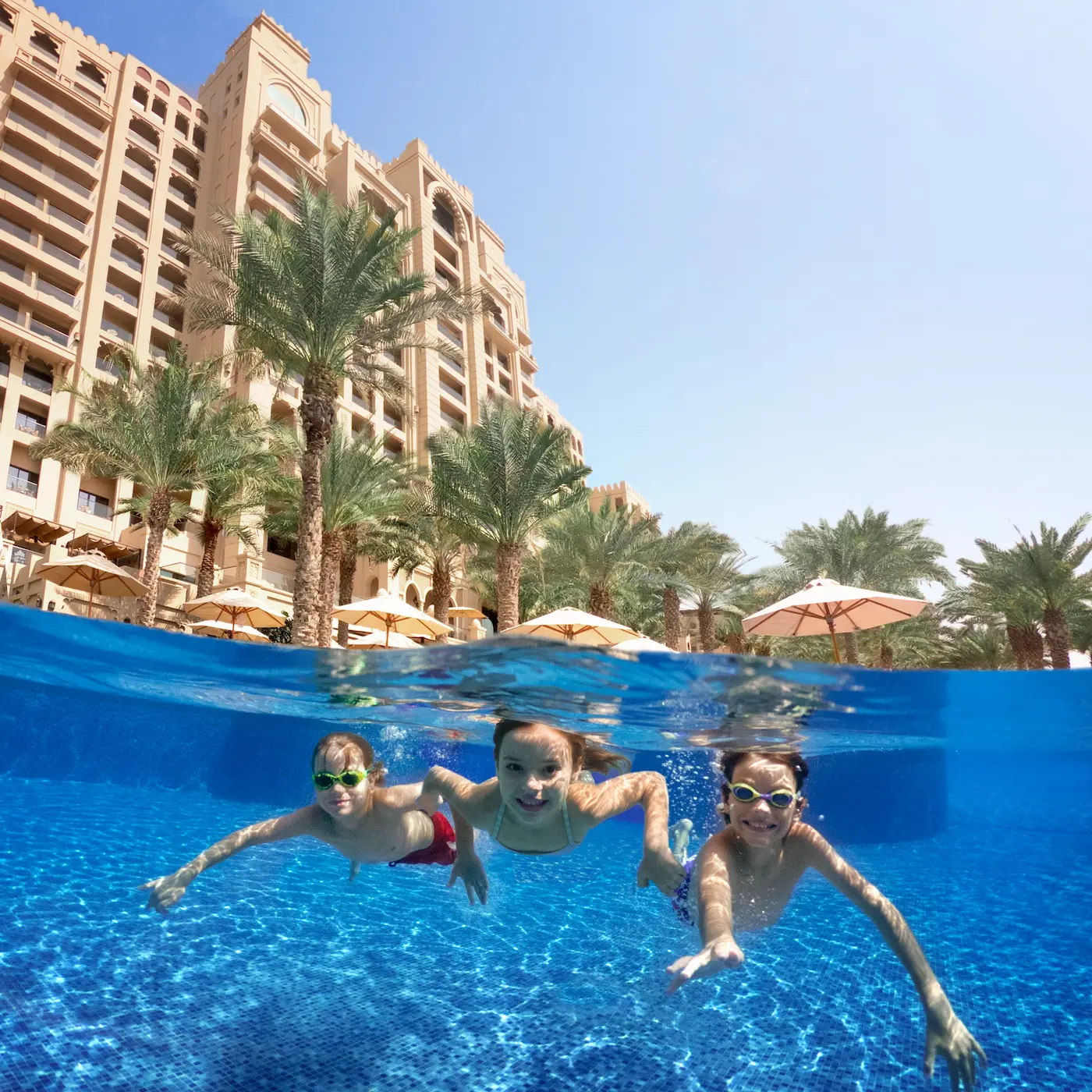 underwater view of children swimming in family pool at fairmont the palm dubai resort