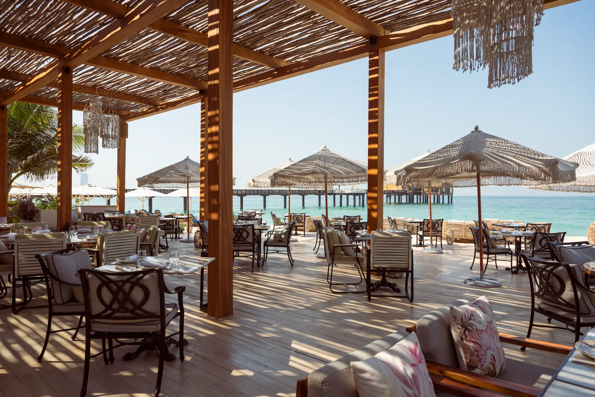 interior of french riviera beach at jumeirah al qasr featuring elegant coastal décor, soft lighting and relaxed beachfront dining atmosphere
