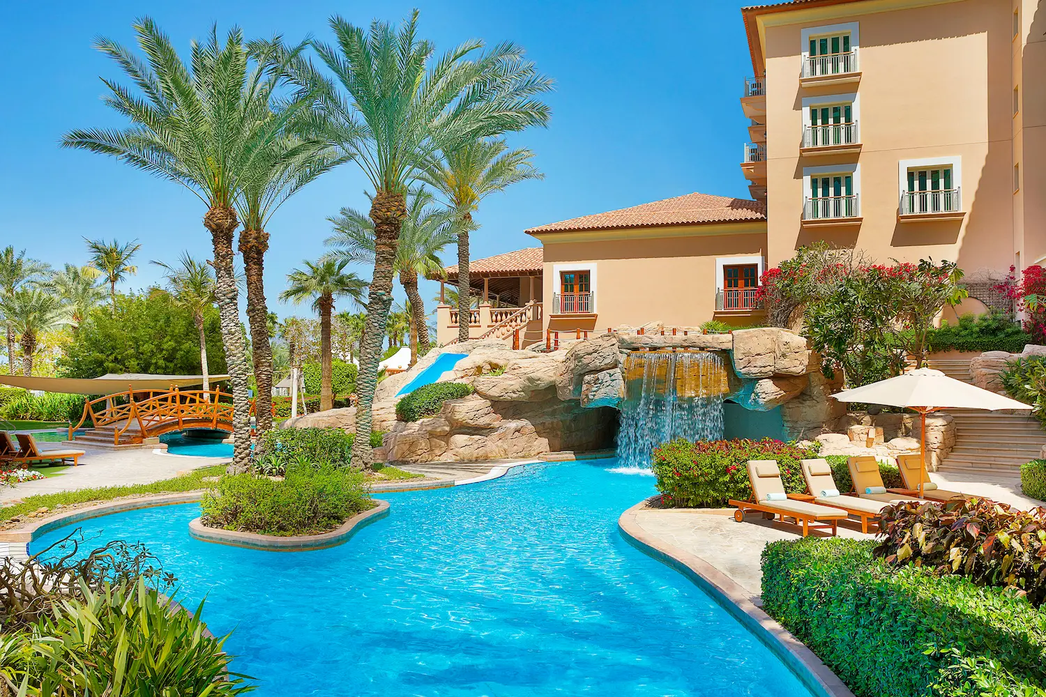 ghoroob pool view at the ritz-carlton dubai jbr featuring relaxed poolside setting, sun loungers, and landscaped gardens at this luxury beachfront hotel in dubai marina