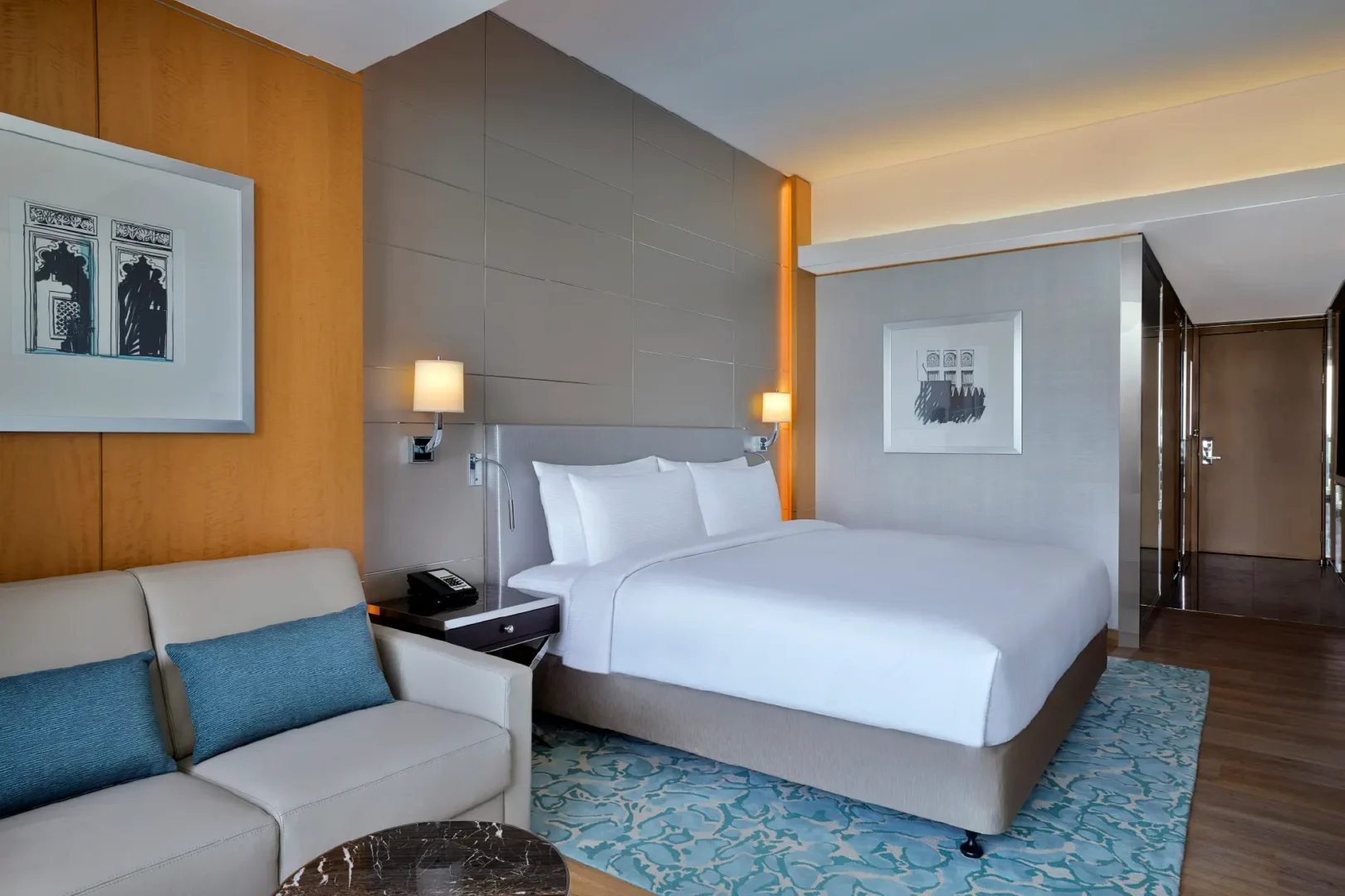 king guest room with plush bed, sofa seating, bedside table and warm ambient lighting