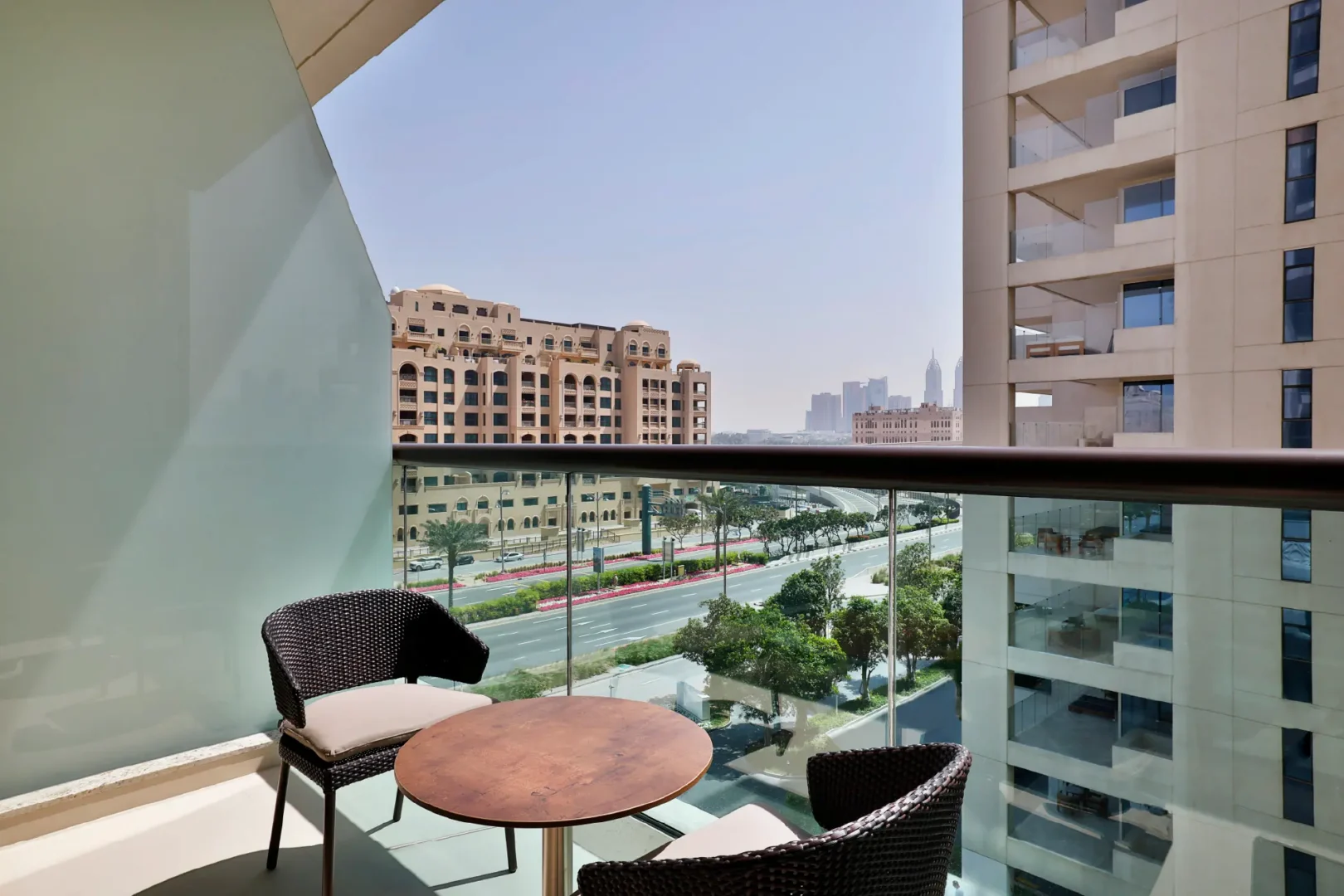 private balcony with outdoor table and chairs overlooking palm jumeirah road and dubai skyline