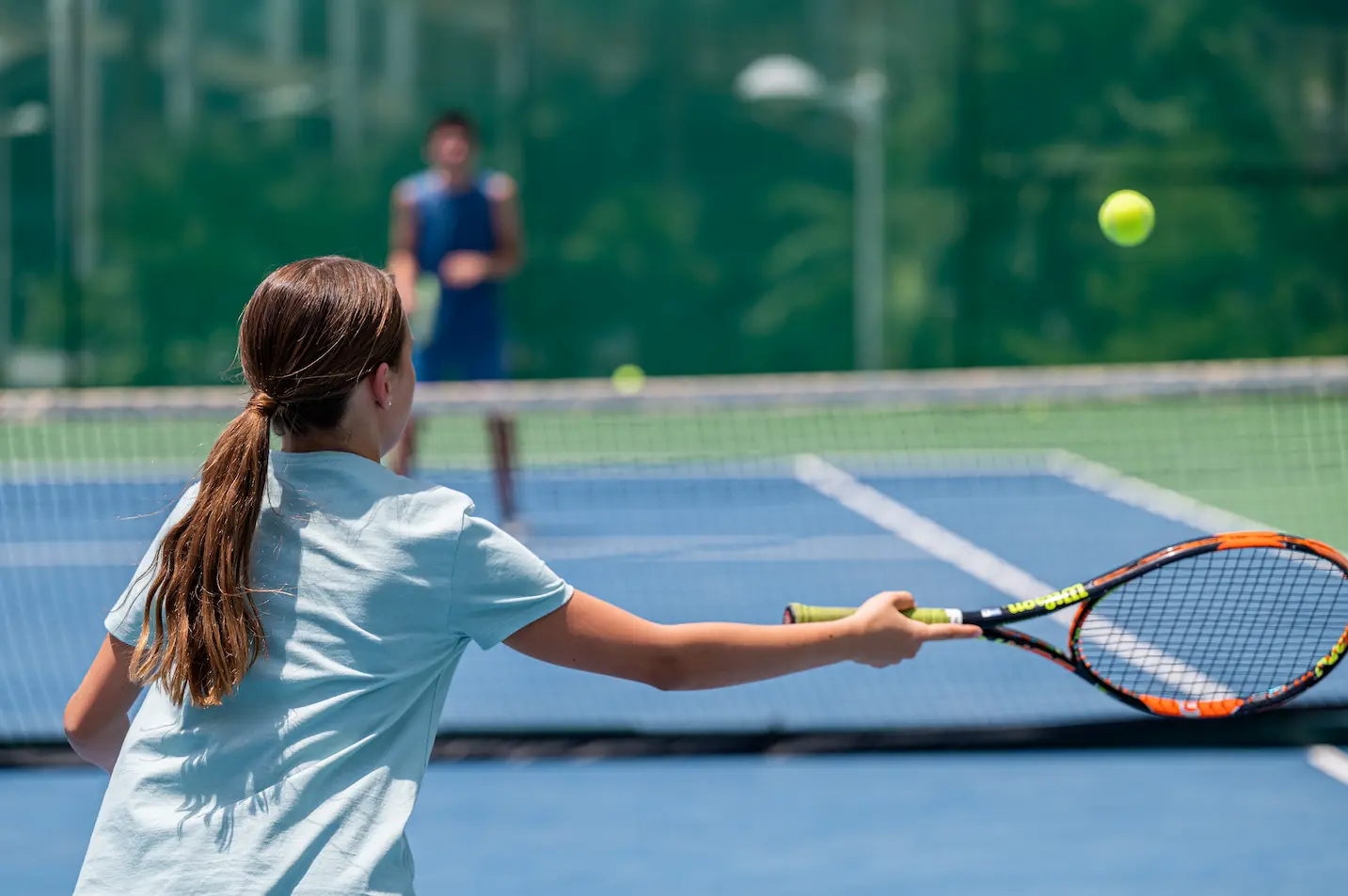 daughter returning tennis ball during family lesson at jumeirah beach hotel tennis court