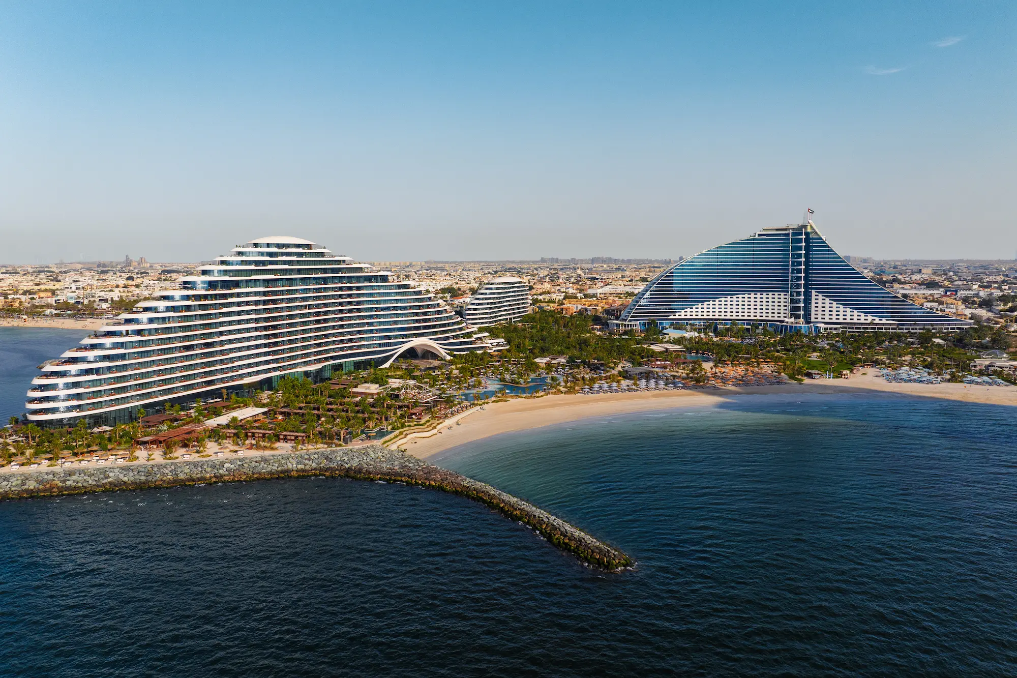 drone shot of jumeirah marsa al arab showing jumeirah beach hotel view at Jumeirah Beach Hotel with arabian gulf, resort buildings and coastline