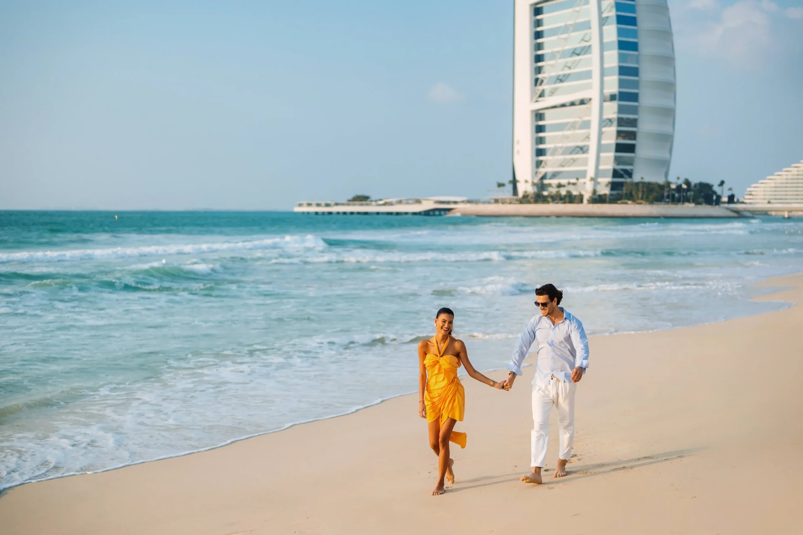 couple embracing and walking on the beach near shimmers restaurant at jumeirah mina a’salam dubai