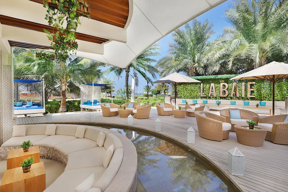 la baie lounge terrace at the ritz-carlton dubai jbr featuring relaxed beachfront seating, poolside views, and stylish outdoor dining in dubai marina