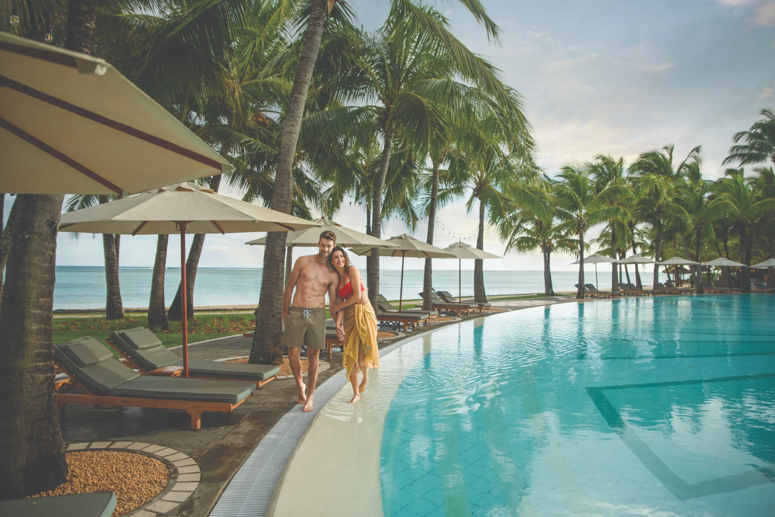 paradis beachcomber mauritius couple relaxing beside the resort pool in a luxury tropical setting