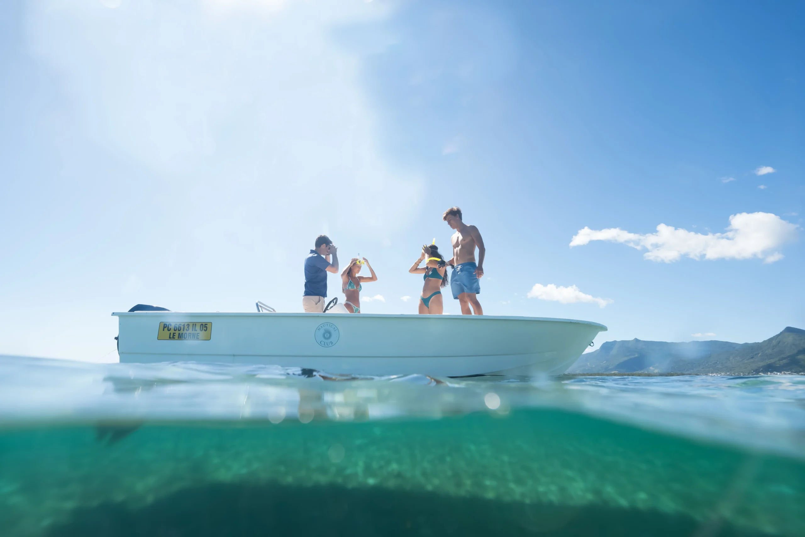 paradis beachcomber mauritius family enjoying boat watersports on the crystal clear lagoon surrounded by tropical scenery
