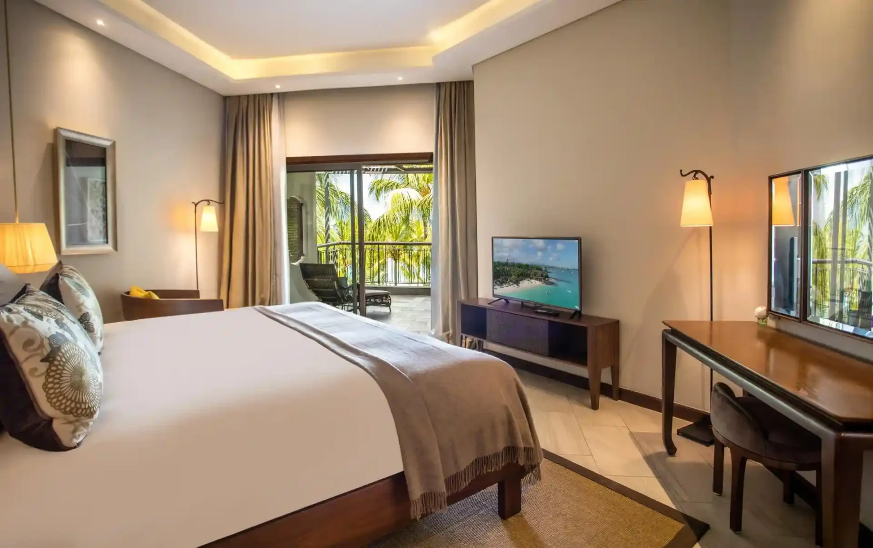 royal palm penthouse suite bedroom with king-size bed, nightstands, lamps, and large windows