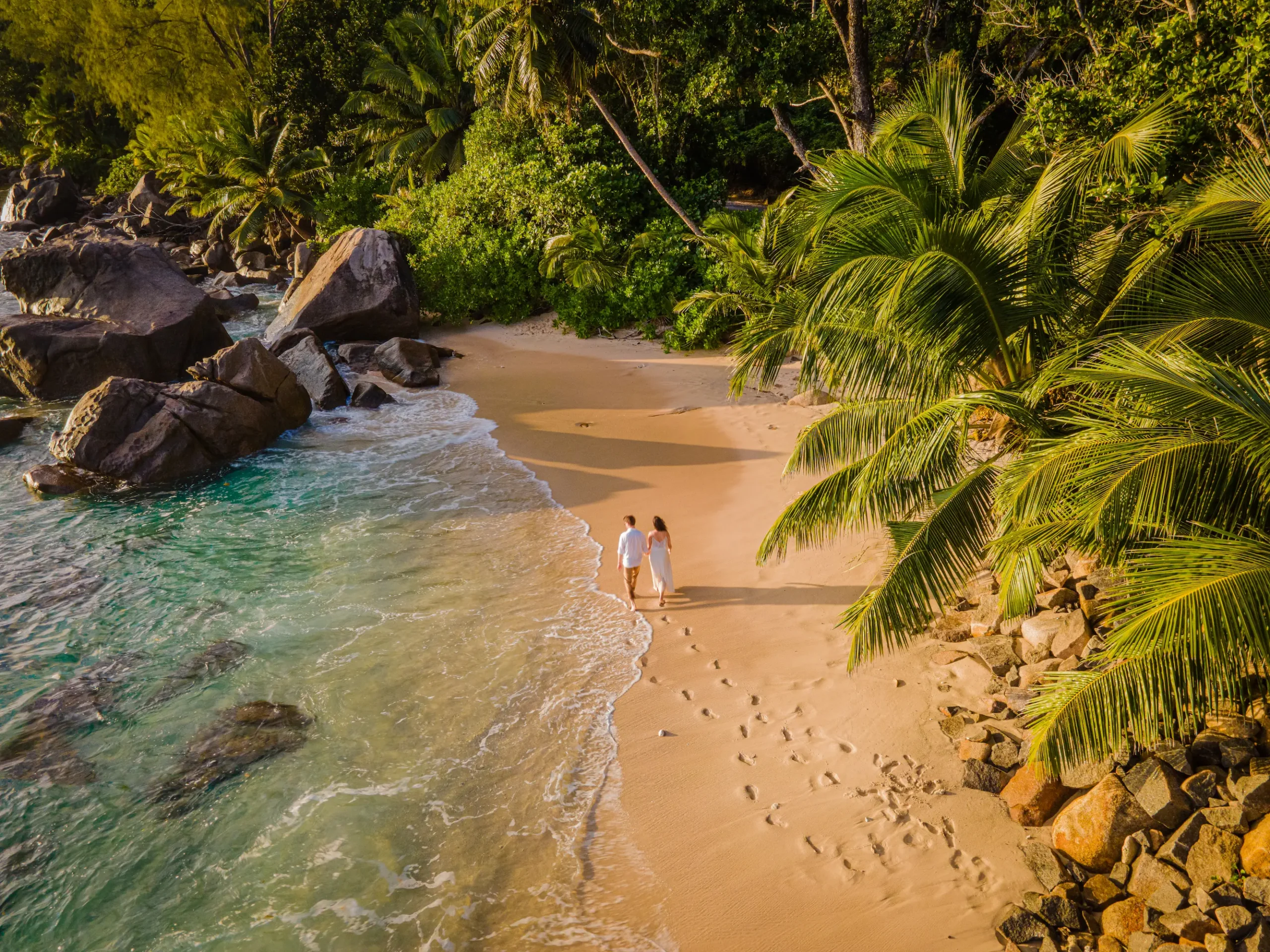 seychelles couples on beach with tropical oceanfront setting and soft white sand