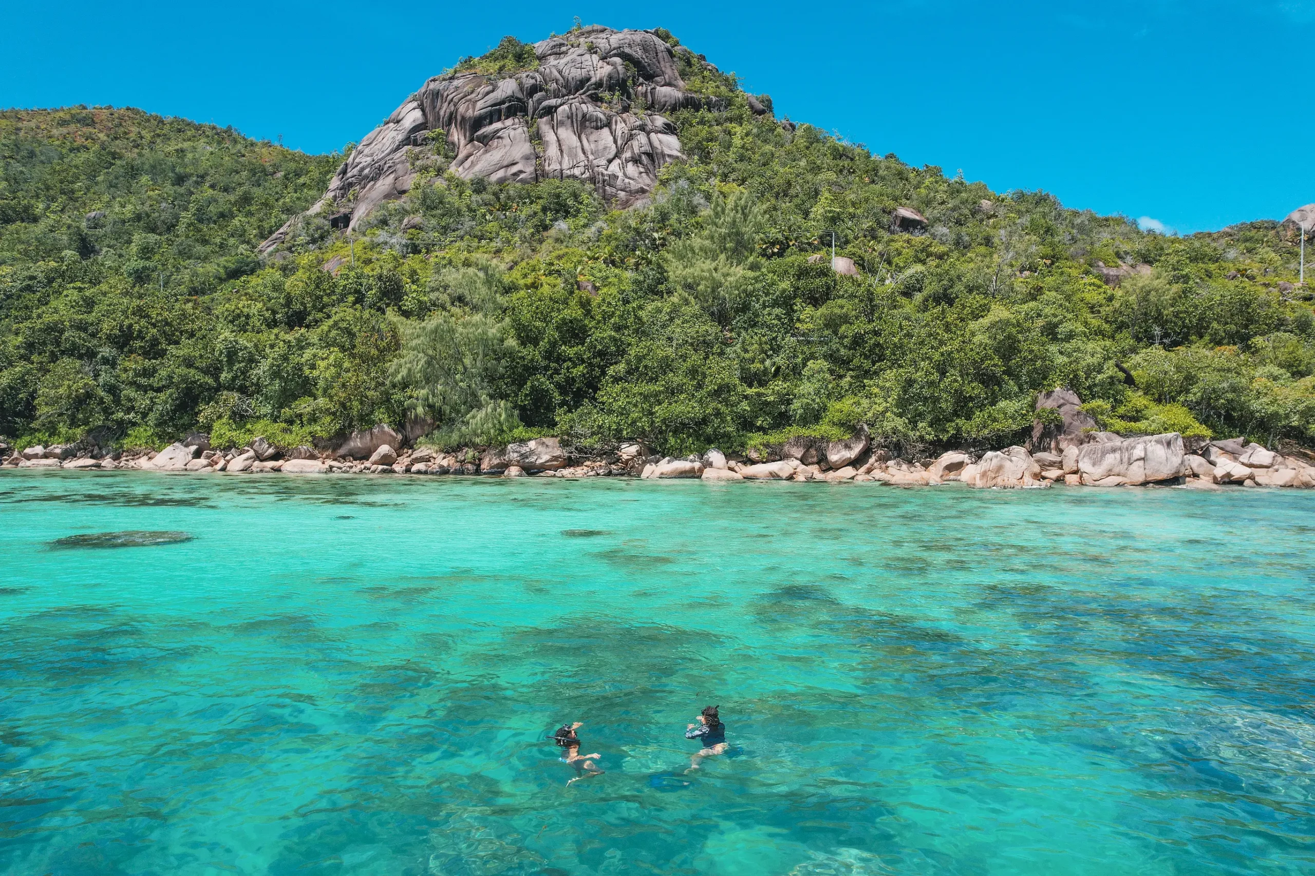 seychelles praslin swimming in tropical beach lagoon with clear turquoise water and soft sand shoreline