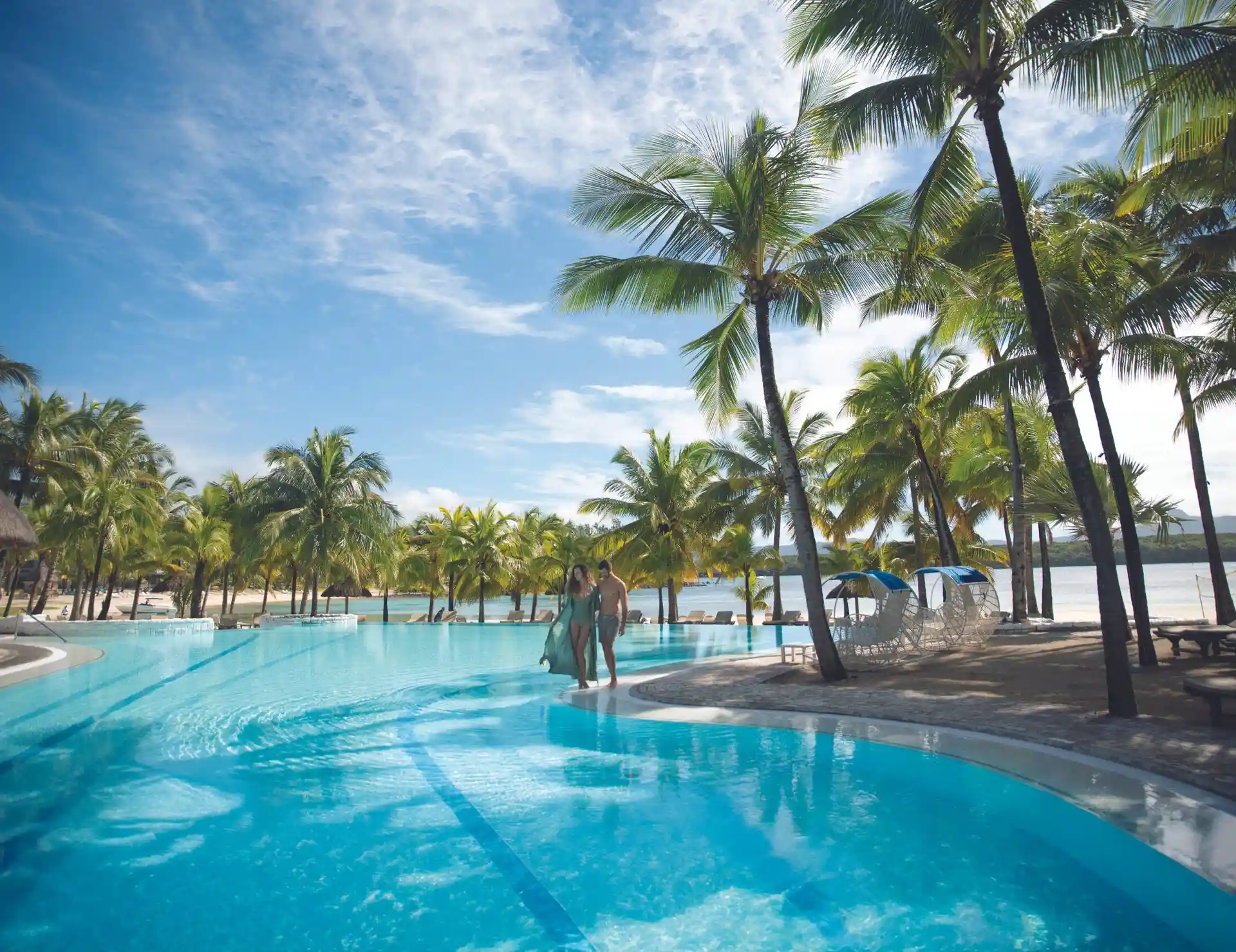 main pool at shandrani beachcomber resort and spa with turquoise water, sun loungers, and tropical garden surroundings