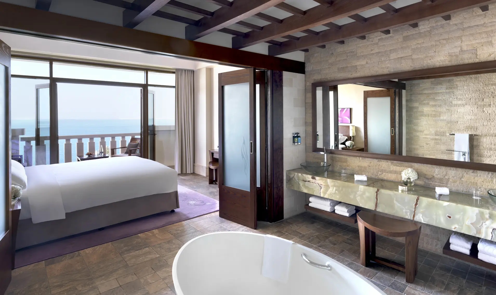 opera suite at sofitel dubai the palm with luxurious living space, king bed, modern decor, spacious bathroom, and private balcony with sea or resort views