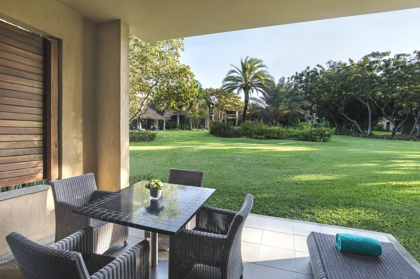 trou aux biches 2 bedroom family suite terrace with outdoor seating, ocean view, and tropical landscaping