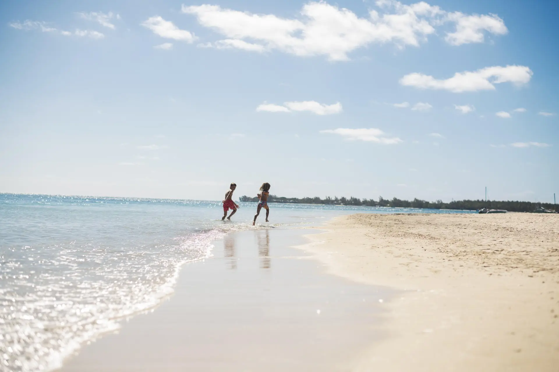 trou-aux-biches mauritius beach with white sand, clear turquoise water, and swaying palm trees