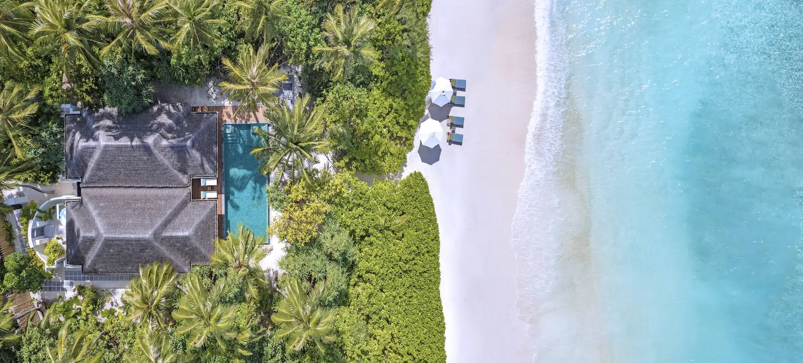 elevated aerial view of the family beach pool villa at anantara kihavah maldives villas surrounded by turquoise shoreline and lush greenery