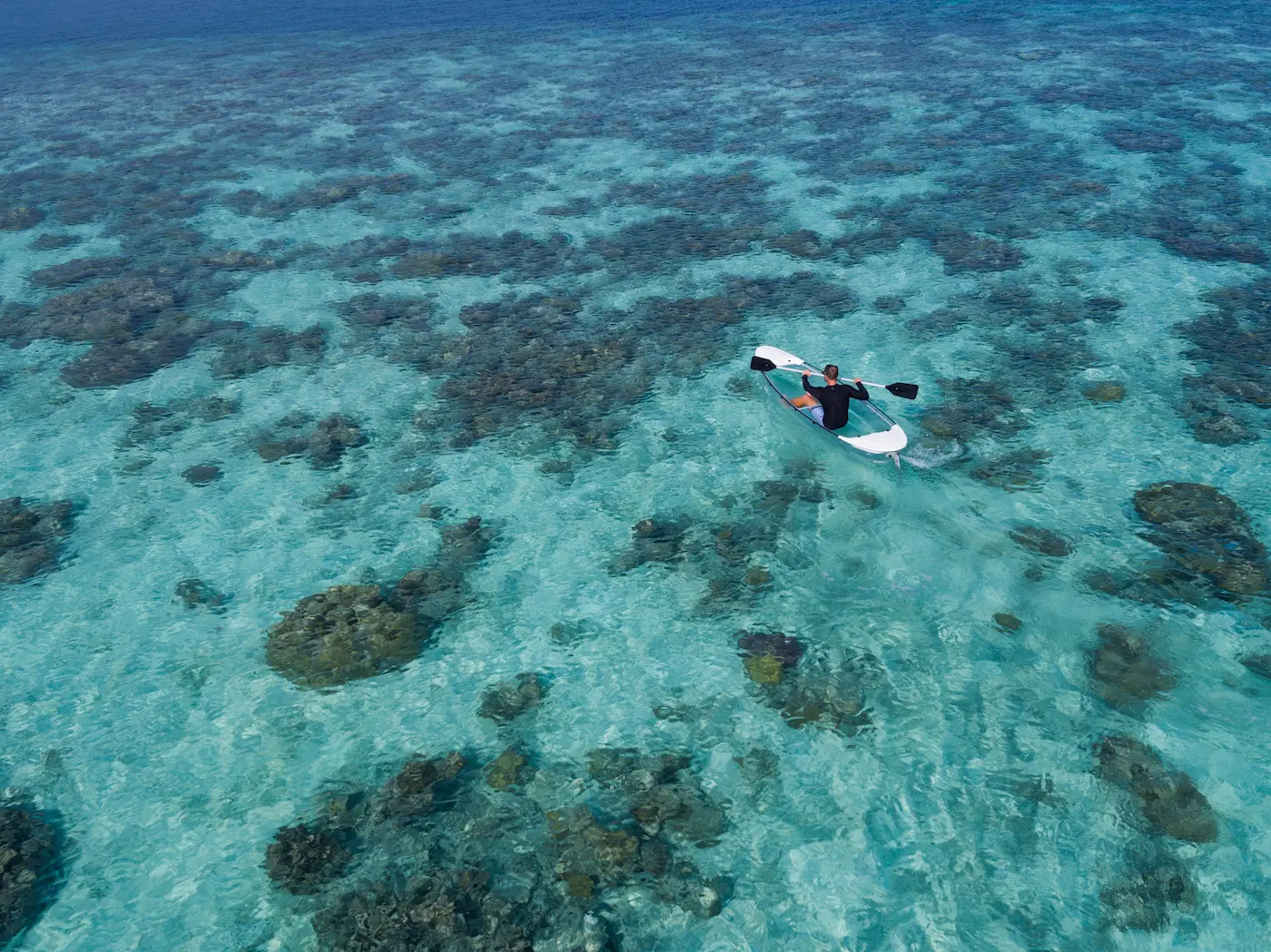 guest kayaking across the calm turquoise lagoon at anantara kihavah maldives villas enjoying a serene ocean adventure