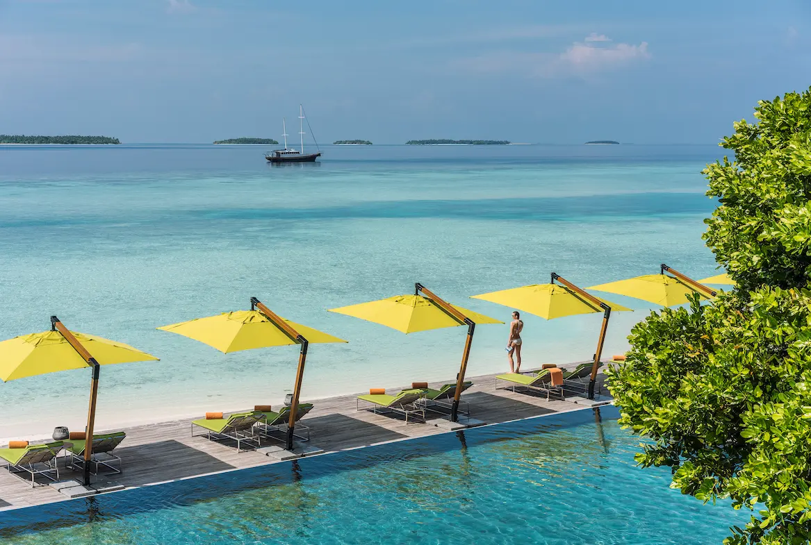 relaxed poolside lifestyle scene at manzaru in anantara kihavah maldives villas overlooking shimmering turquoise water