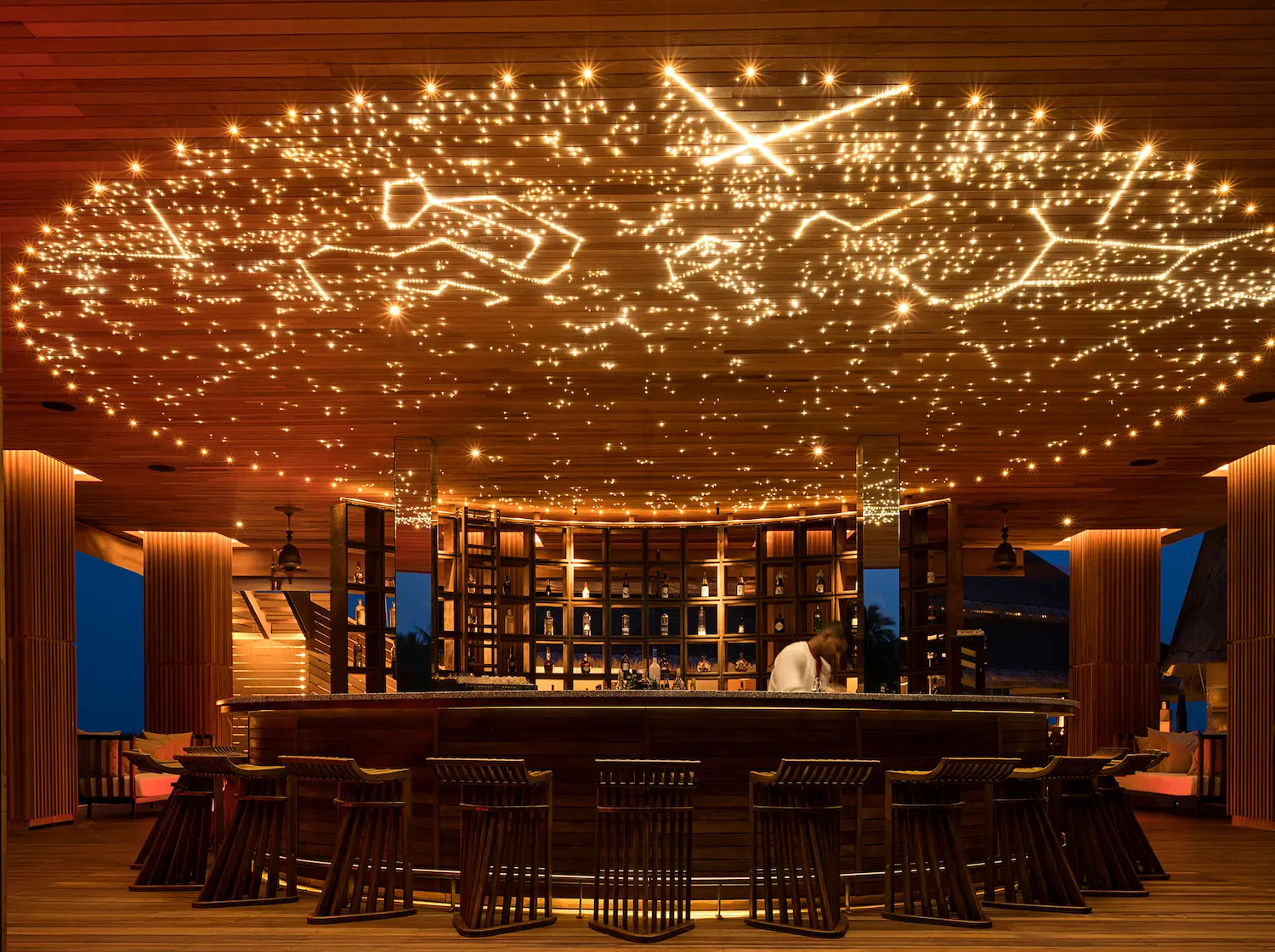 evening view of the sky bar at anantara kihavah maldives villas featuring warm ceiling lights and open ocean ambiance