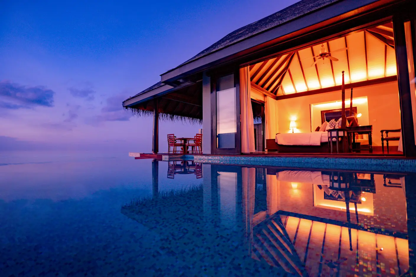 luxury overwater pool villa interior at anantara kihavah maldives villas bathed in warm sunset light