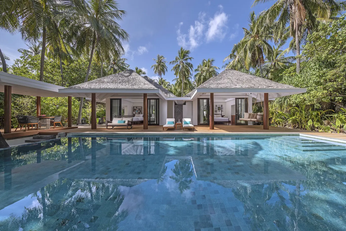 daylit exterior of the two bedroom family beach pool villa at anantara kihavah maldives villas framed by tropical greenery and beachside calm