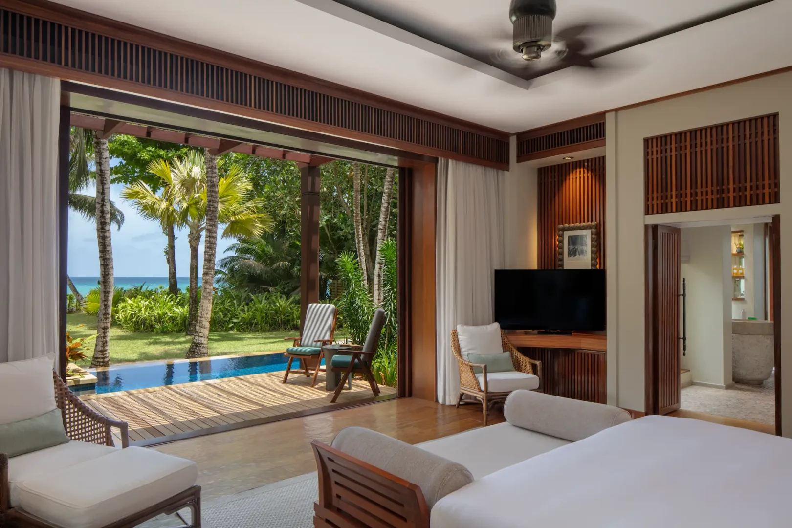 bed view from a beach pool villa at Anantara Maia Seychelles Villas overlooking a private pool and tropical beachfront with ocean views through large windows