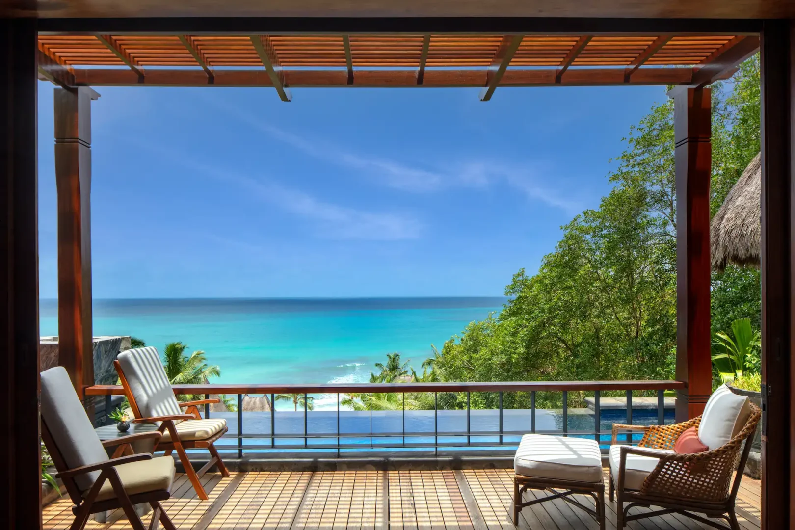 seating area in an ocean view pool villa at Anantara Maia Seychelles Villas overlooking a private pool with views of tropical greenery and the ocean