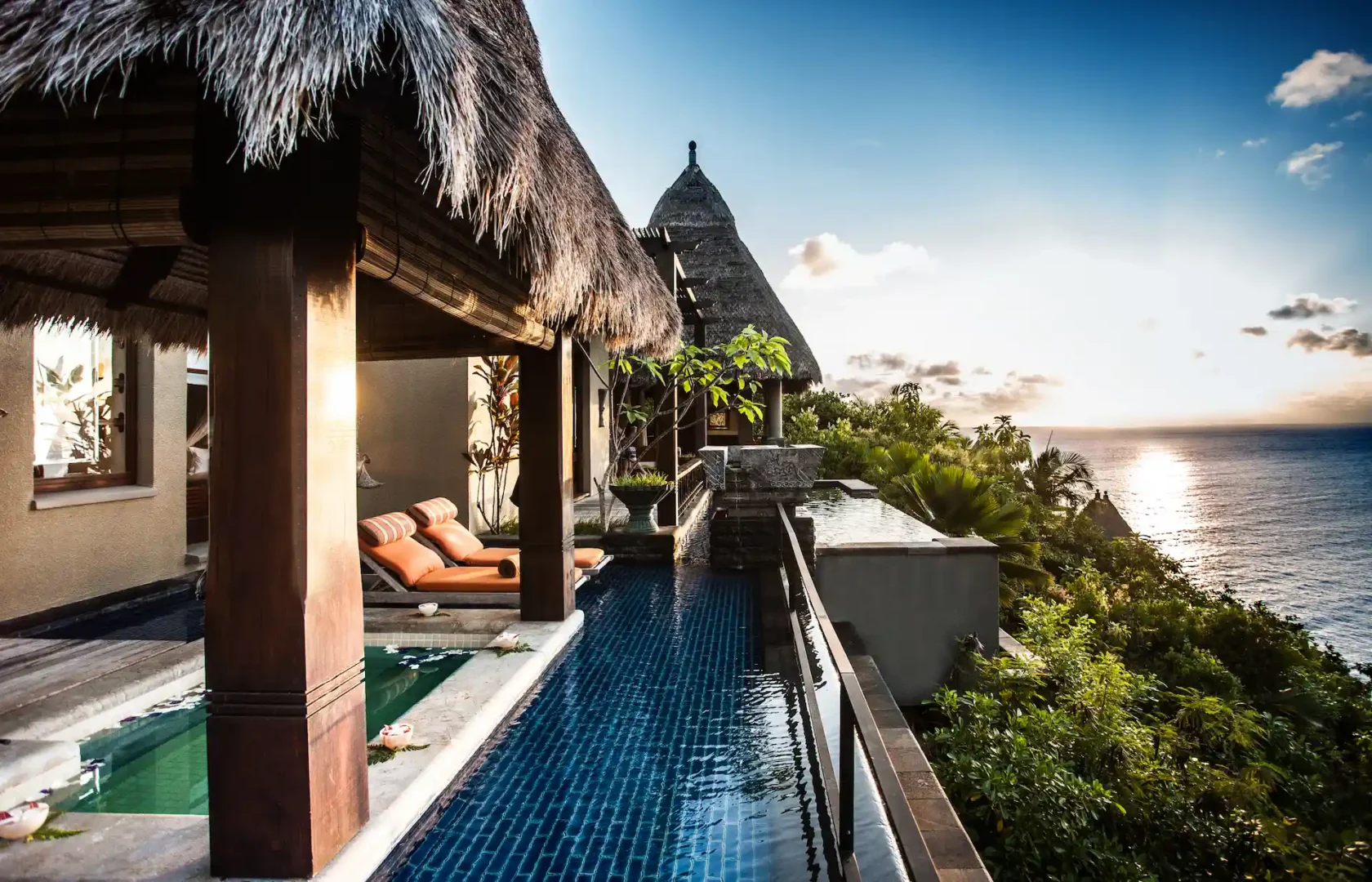 sunset view from an ocean view pool villa at Anantara Maia Seychelles Villas with warm colors over the ocean and tropical landscape