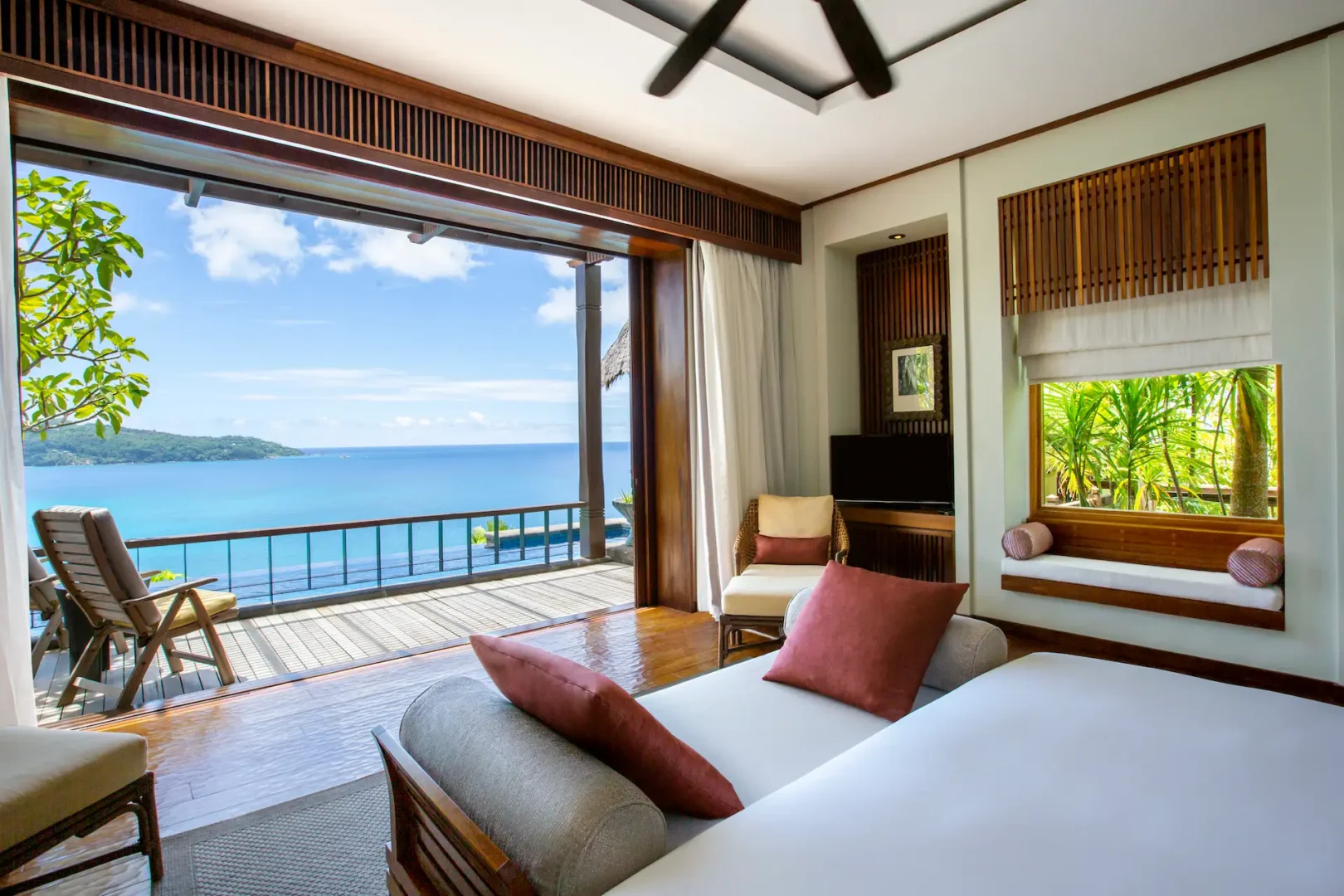 bed view from a premier ocean view pool villa at Anantara Maia Seychelles Villas overlooking a private pool, tropical greenery, and the ocean through large windows