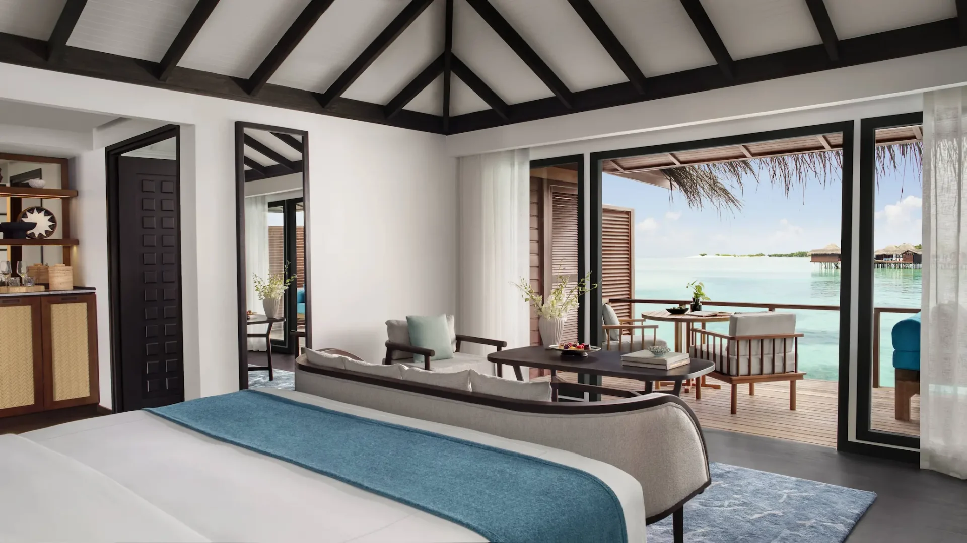overwater villa bedroom view at anantara veli maldives resort overlooking a calm turquoise lagoon