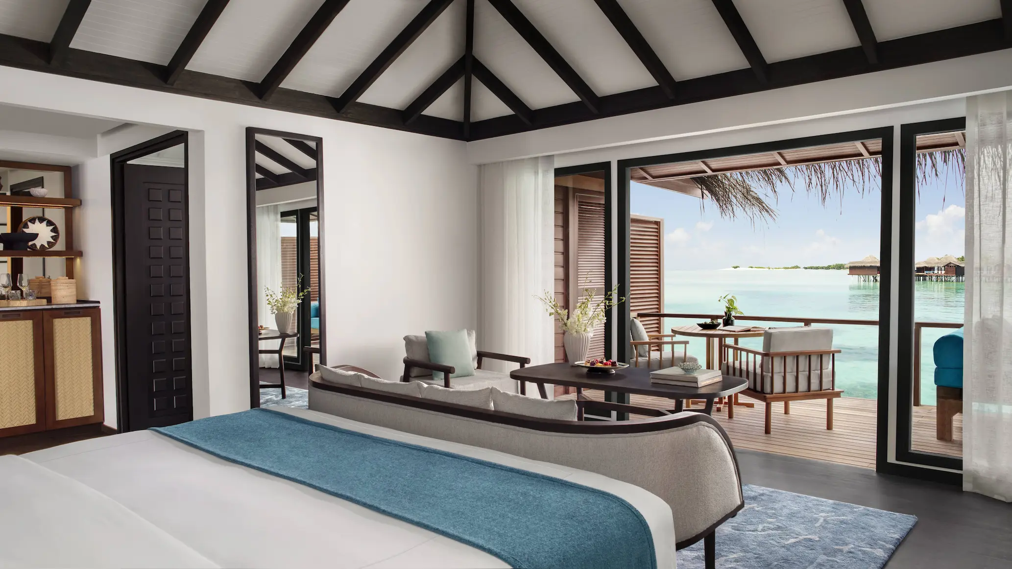 overwater villa bedroom view at anantara veli maldives resort overlooking a calm turquoise lagoon