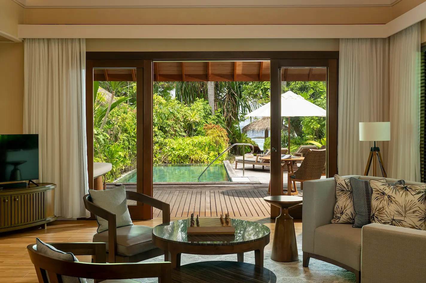 living area of the baros residence at baros maldives opening onto a deck with serene island views