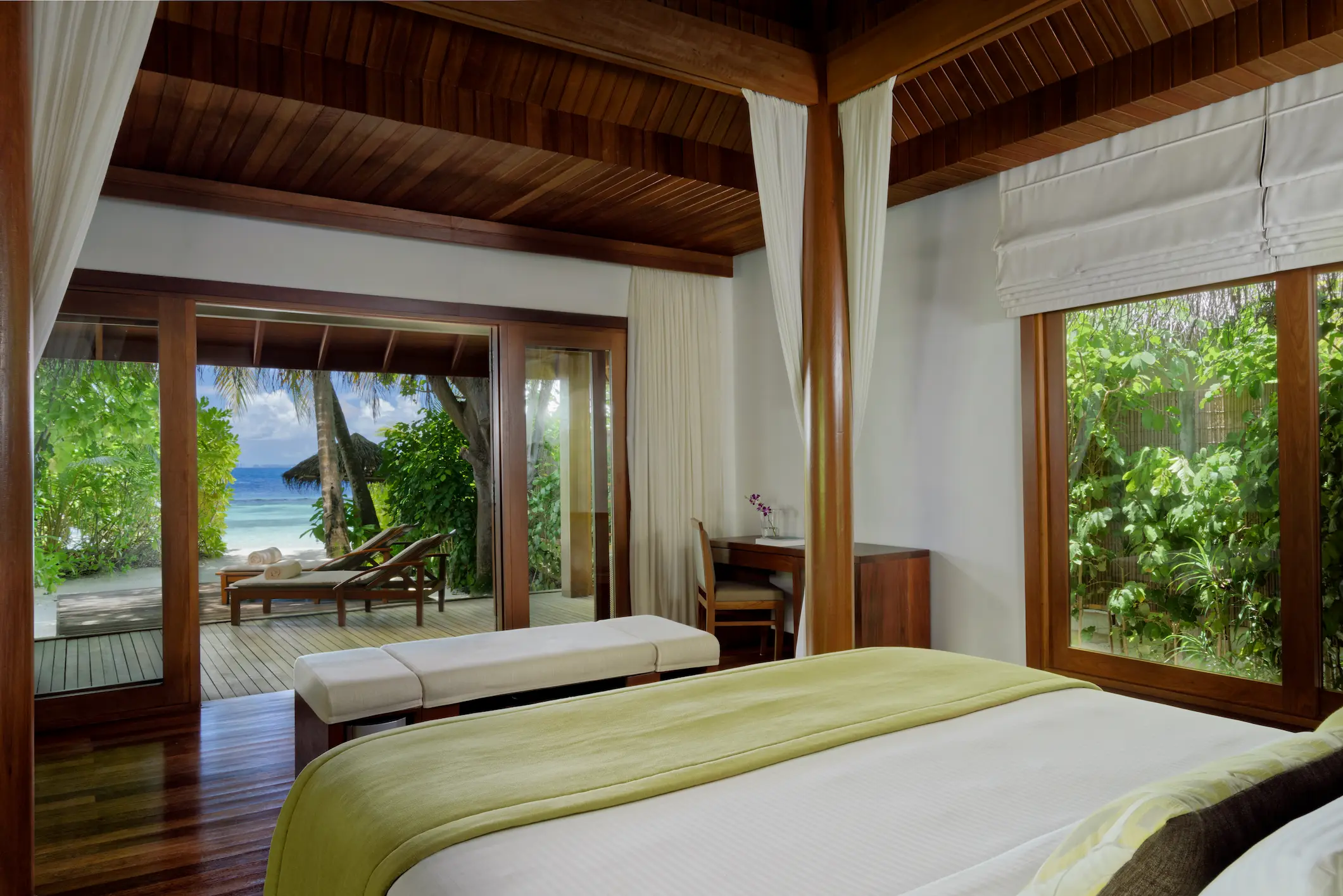 bed area of the baros villa at baros maldives with warm island design and soft natural tones