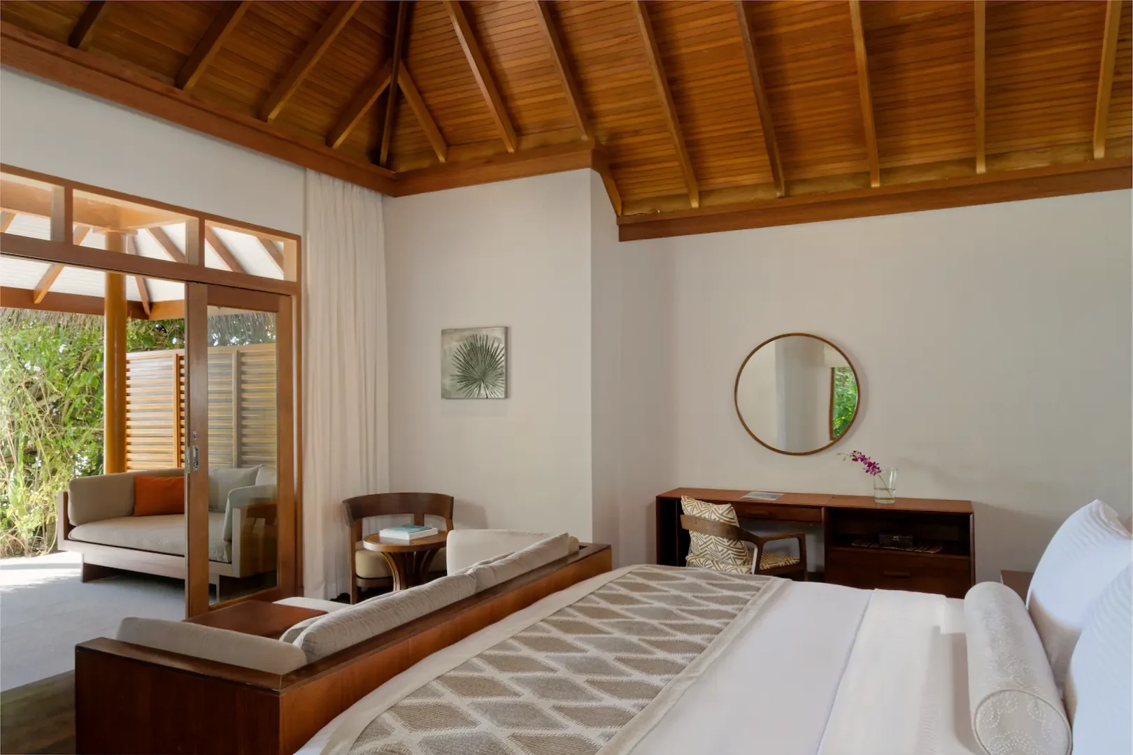 bedroom inside the deluxe villa at baros maldives with warm island design and soft natural light