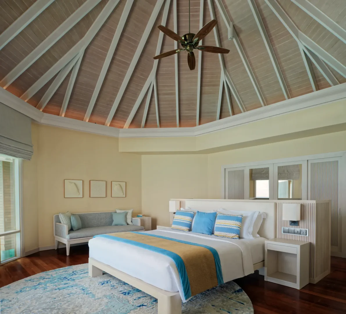 bed area of the water villa at baros maldives with soft island light and elegant coastal design