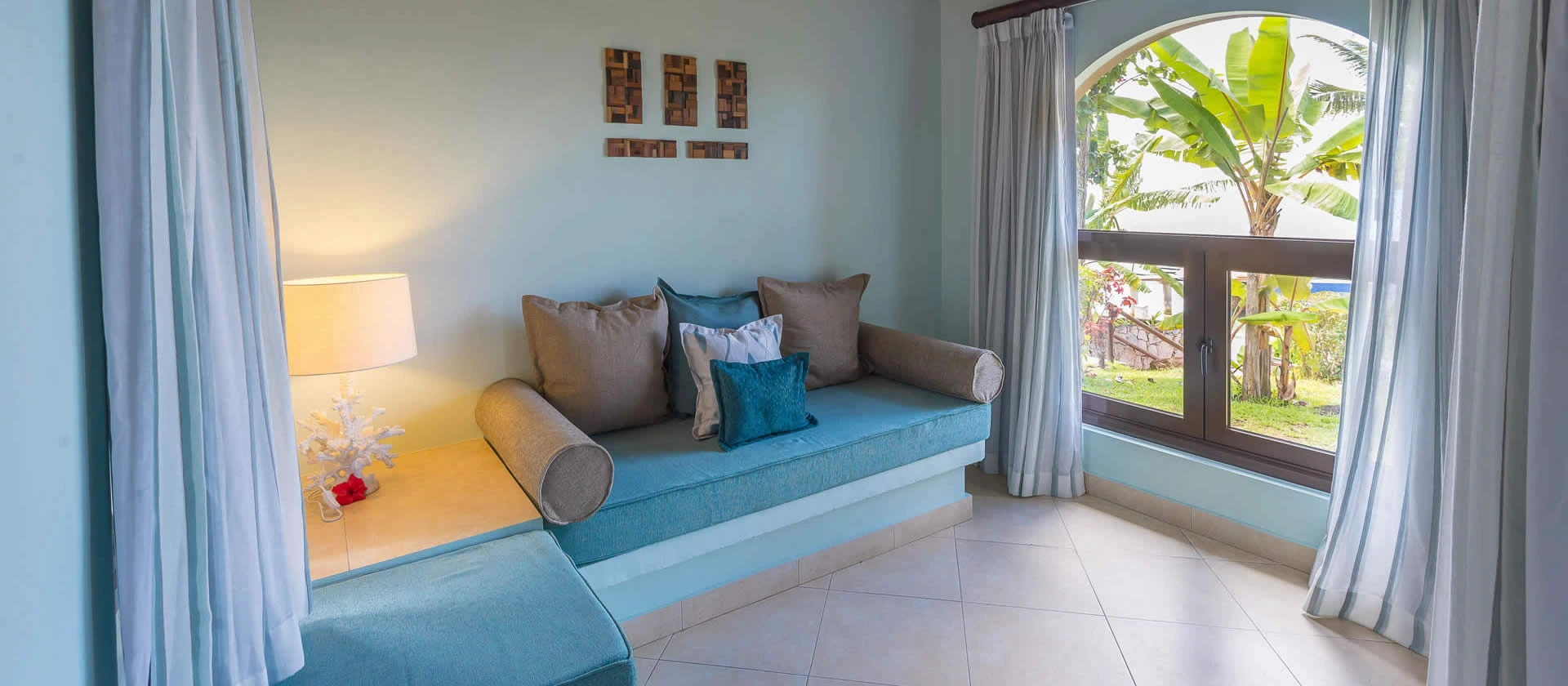 coco de mer seychelles standard room lounge with comfortable seating, tropical décor, and natural light from large windows
