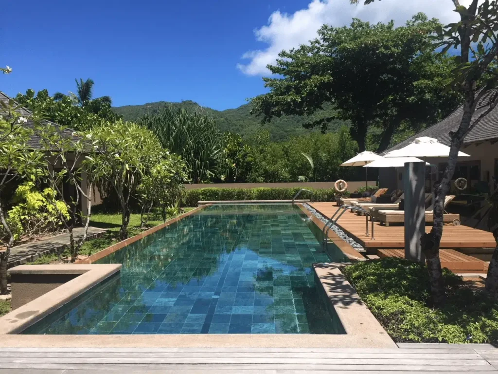 pool at Constance Ephelia surrounded by tropical gardens with sun loungers and a relaxed resort setting