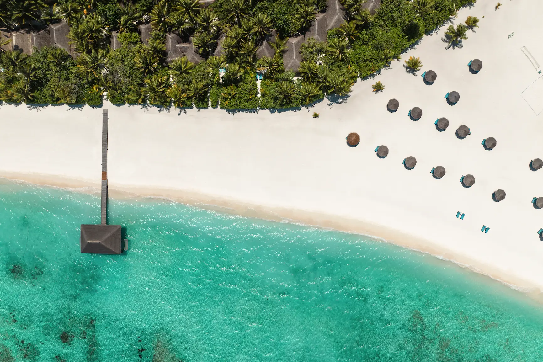 birds eye view of constance moofushi maldives showing the island surrounded by bright turquoise lagoon waters