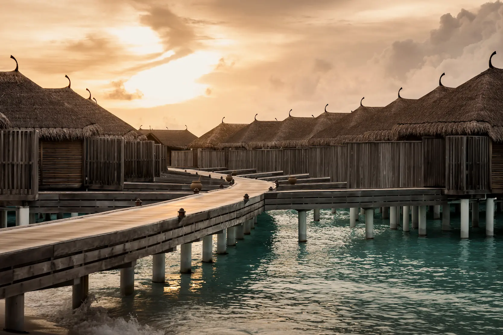 exterior view of the water villas at constance moofushi maldives set above a clear turquoise lagoon