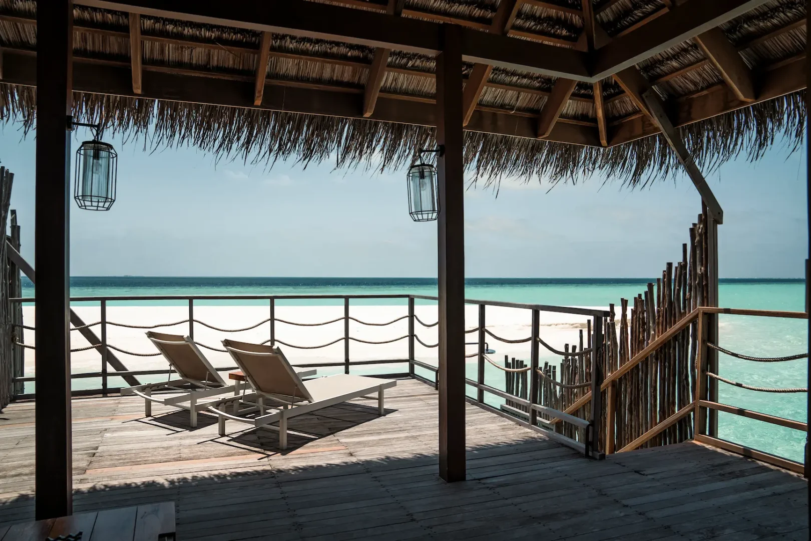 open balcony of the senior water villa at constance moofushi maldives with calm ocean views warm wood finishes and relaxed island seating