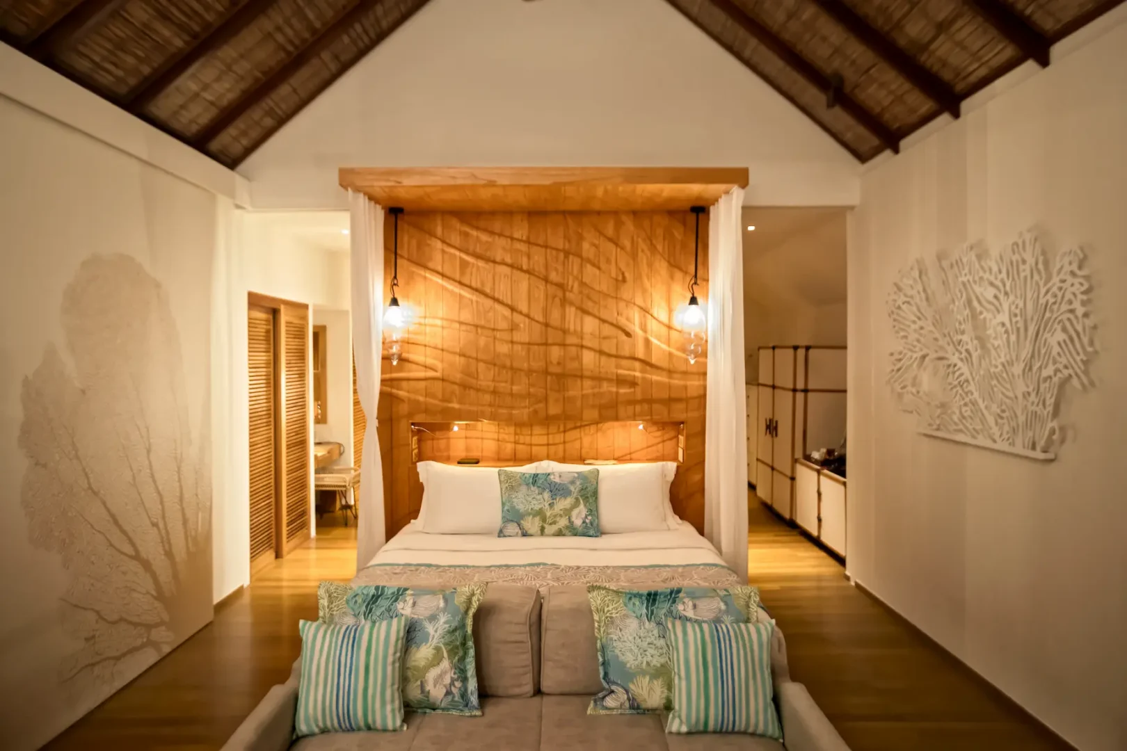 serene bedroom inside the senior water villa at constance moofushi maldives featuring warm timber details soft natural light and tranquil lagoon ambiance