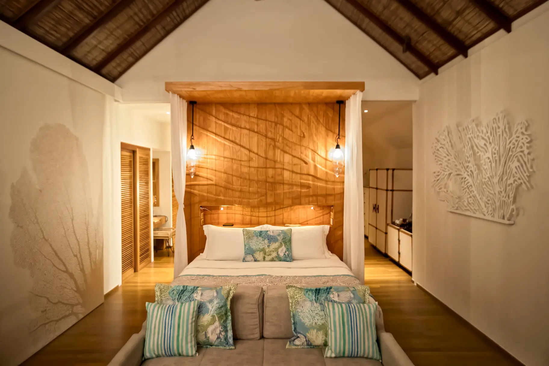 serene bedroom inside the senior water villa at constance moofushi maldives featuring warm timber details soft natural light and tranquil lagoon ambiance